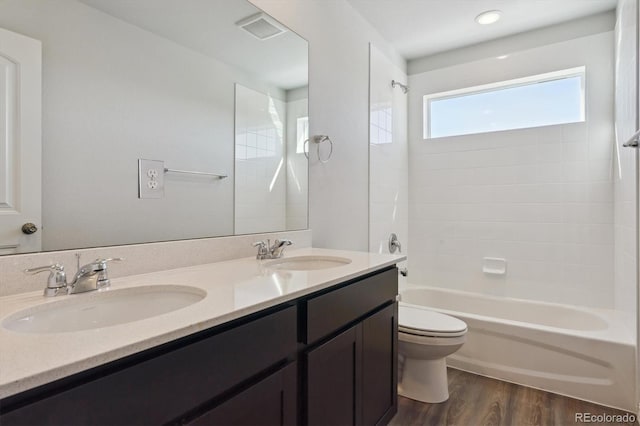 full bathroom featuring hardwood / wood-style flooring, tiled shower / bath, vanity, and toilet