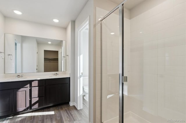 bathroom with a shower with door, wood-type flooring, vanity, and toilet