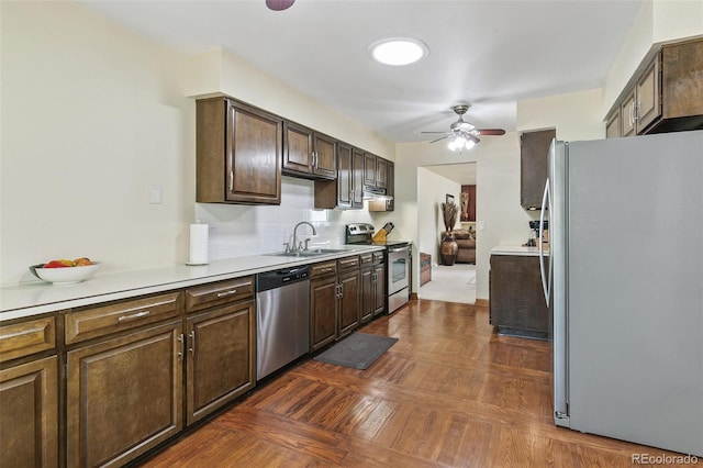 kitchen with stainless steel appliances, light countertops, a sink, and dark brown cabinetry