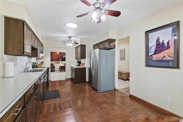 kitchen featuring dark brown cabinetry, baseboards, freestanding refrigerator, light countertops, and a sink