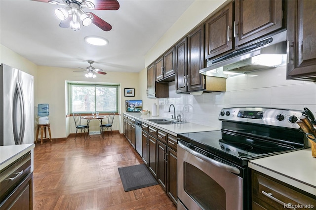 kitchen with stainless steel appliances, dark brown cabinets, light countertops, under cabinet range hood, and a sink