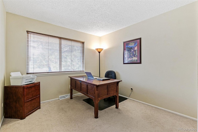 office featuring baseboards, visible vents, a textured ceiling, and light colored carpet