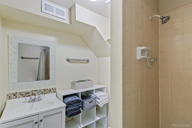 full bath featuring vanity, tasteful backsplash, a tile shower, and visible vents