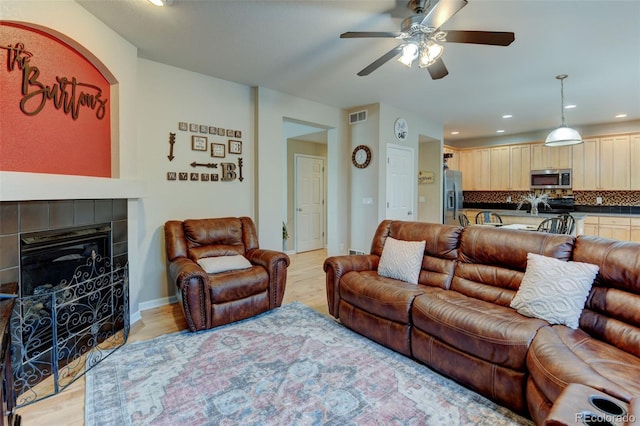 1995 E 166th Ave, Thornton, CO 80602 - living area with light wood-style flooring, a ceiling fan, a tile fireplace, recessed lighting, and baseboards