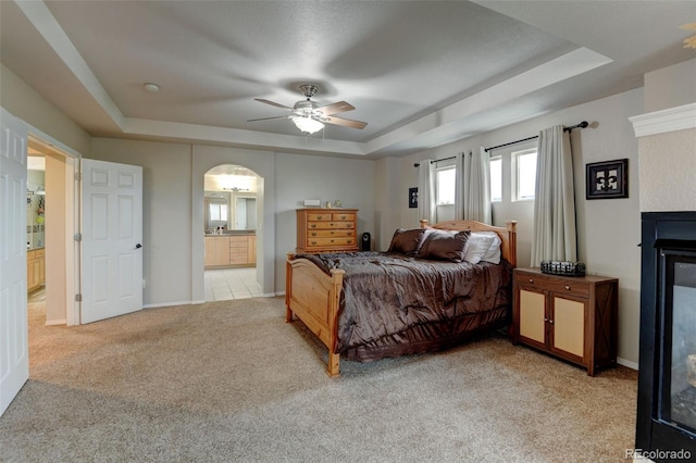 1995 E 166th Ave, Thornton, CO 80602 - bedroom featuring a raised ceiling, light carpet, ensuite bath, arched walkways, and baseboards