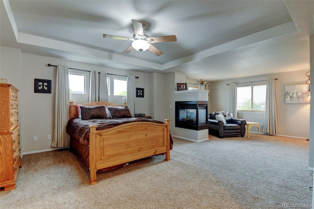1995 E 166th Ave, Thornton, CO 80602 - bedroom with a raised ceiling, a multi sided fireplace, light carpet, baseboards, and a ceiling fan