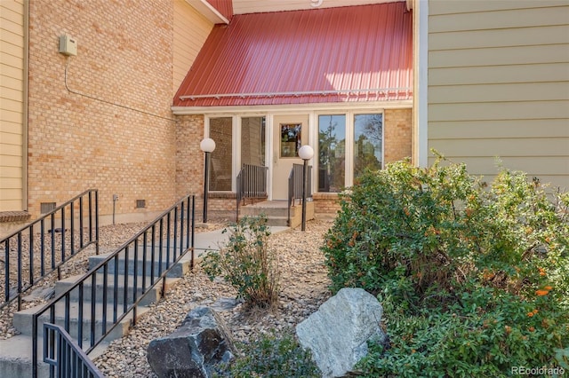 property entrance with metal roof, brick siding, and crawl space