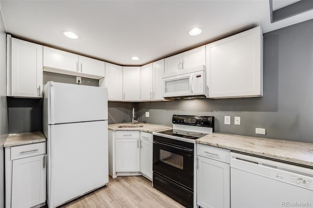 kitchen featuring white appliances, light wood-style flooring, white cabinets, and a sink