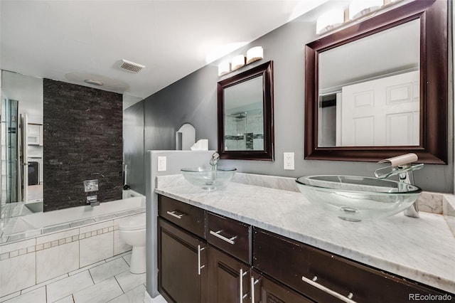 full bath with toilet, double vanity, a sink, and visible vents