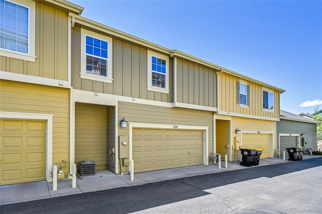 view of property with a garage, board and batten siding, and cooling unit