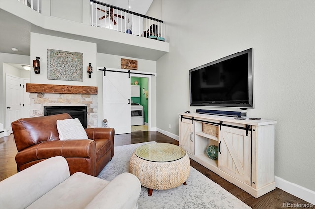 living area with baseboards, a high ceiling, a barn door, and dark wood-type flooring