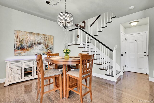 dining area featuring baseboards, stairs, wood finished floors, and a chandelier