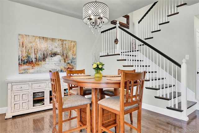 dining area with wood finished floors, a notable chandelier, and stairway
