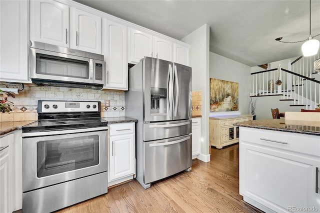 kitchen with appliances with stainless steel finishes, backsplash, light wood finished floors, and white cabinetry