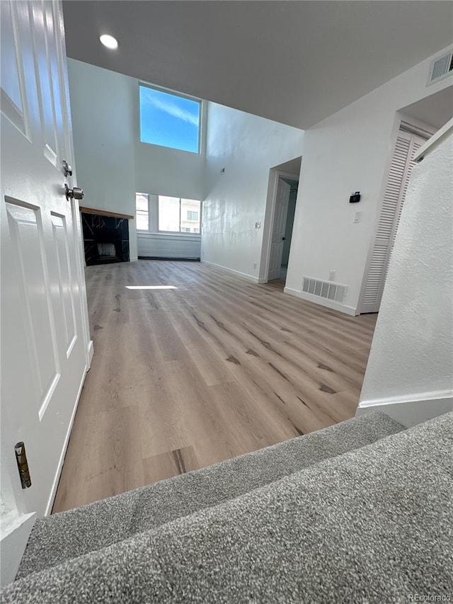 unfurnished living room with a high end fireplace, visible vents, and wood finished floors