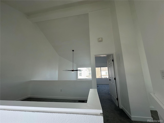 corridor featuring high vaulted ceiling, baseboards, and dark carpet