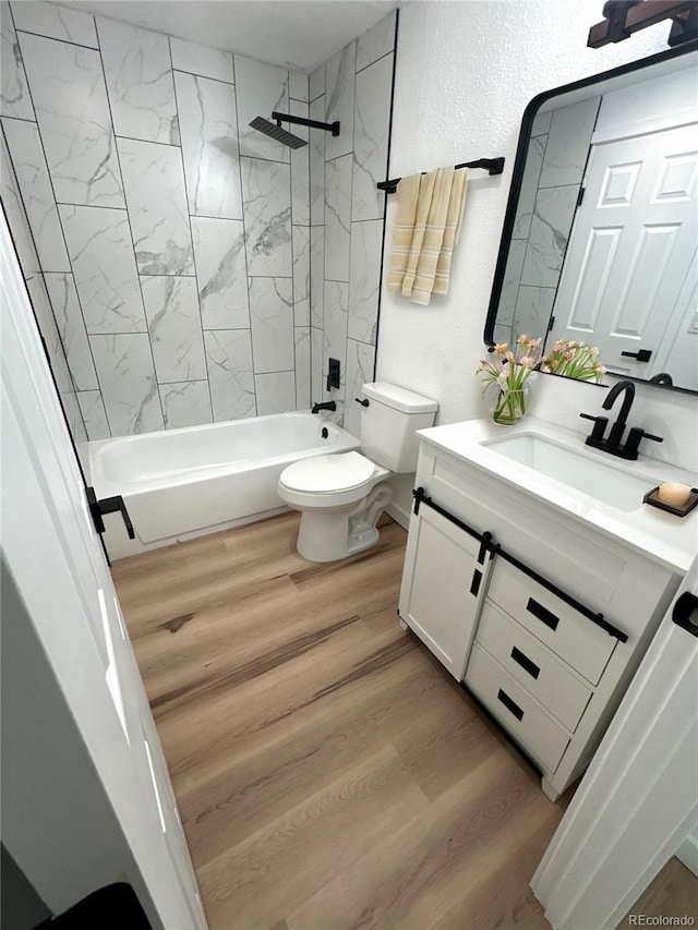 bathroom with shower / bath combination, a textured wall, toilet, wood finished floors, and vanity