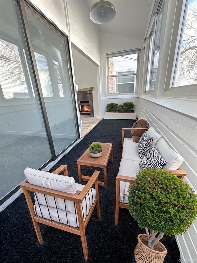 sunroom / solarium featuring lofted ceiling and a lit fireplace