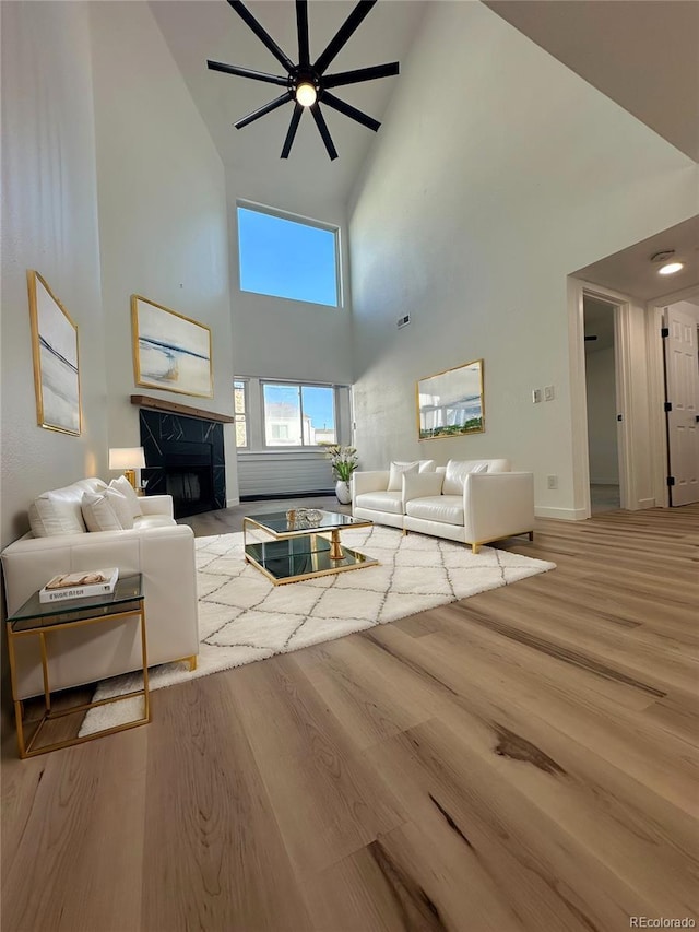 living room featuring a towering ceiling, a premium fireplace, and wood finished floors