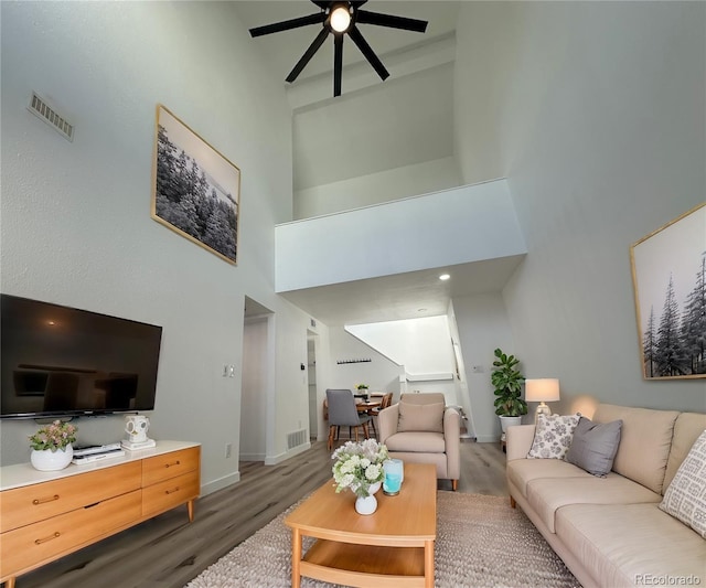 living area with baseboards, ceiling fan, visible vents, and wood finished floors