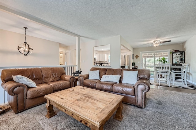 living room with a textured ceiling, ceiling fan with notable chandelier, and carpet