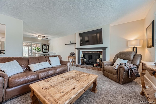 living room featuring a brick fireplace, ceiling fan, carpet floors, and a textured ceiling