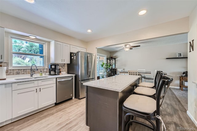 kitchen with sink, white cabinetry, backsplash, appliances with stainless steel finishes, and ceiling fan