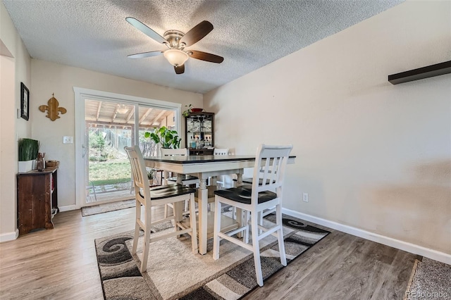 dining space with wood-type flooring, ceiling fan, and a textured ceiling