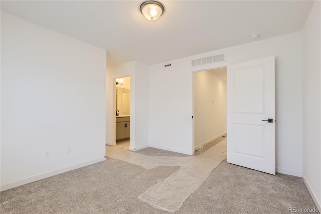 unfurnished bedroom with visible vents, ensuite bath, light carpet, and baseboards