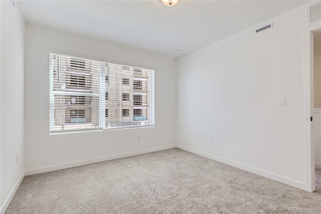 spare room featuring carpet floors, visible vents, and baseboards