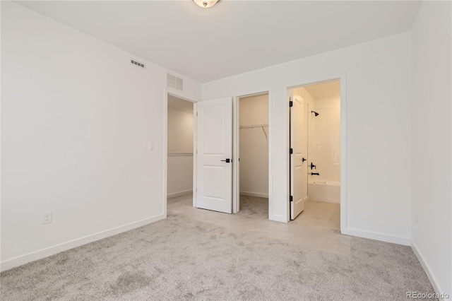 unfurnished bedroom featuring light colored carpet, visible vents, baseboards, and a spacious closet