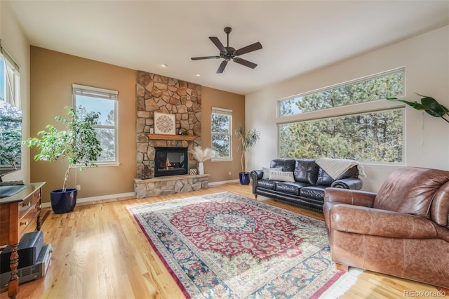 living area with wood finished floors, plenty of natural light, a fireplace, and a ceiling fan