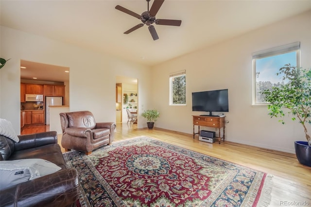 living room with light wood-style floors, ceiling fan, and baseboards