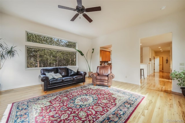 living room with ceiling fan, light wood finished floors, and baseboards