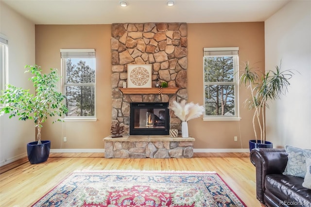 living area featuring a fireplace, baseboards, and wood finished floors