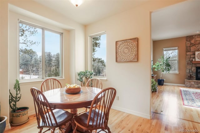 dining area featuring light wood-style floors, a fireplace, and baseboards