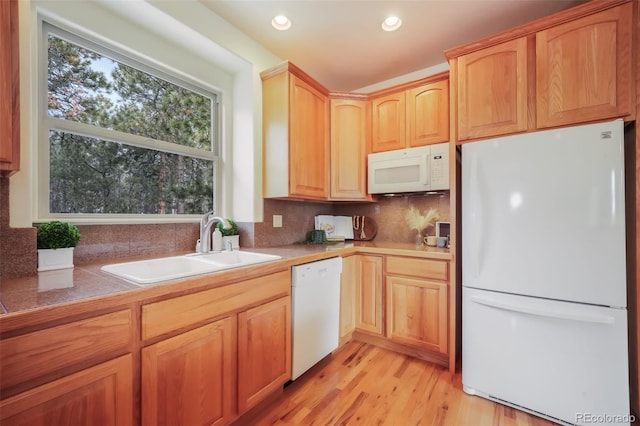 kitchen with light wood finished floors, recessed lighting, backsplash, a sink, and white appliances