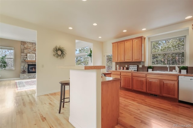 kitchen featuring plenty of natural light, white dishwasher, a fireplace, and a sink