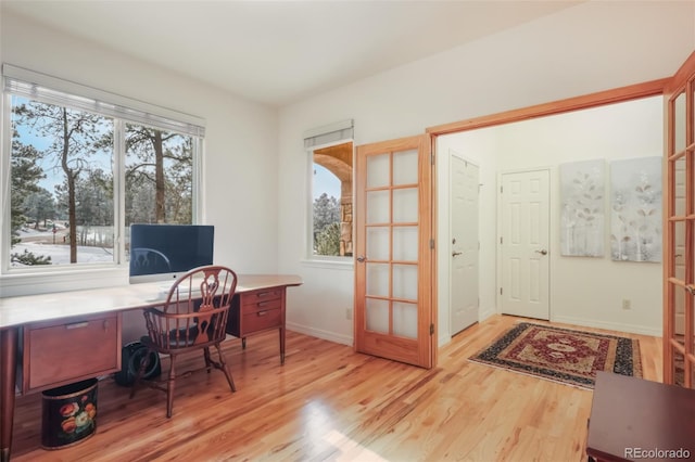 home office with light wood-type flooring, baseboards, and french doors