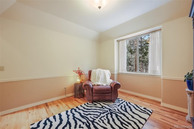 sitting room featuring lofted ceiling, baseboards, and wood finished floors