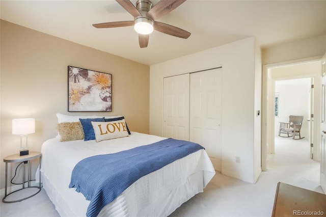 bedroom featuring light carpet, ceiling fan, a closet, and baseboards