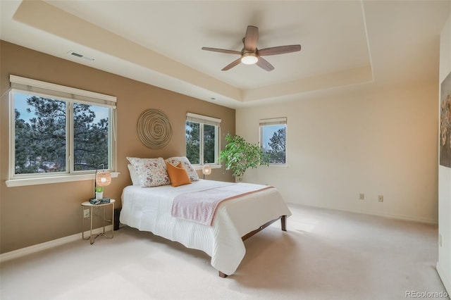 bedroom featuring a ceiling fan, visible vents, baseboards, carpet, and a raised ceiling