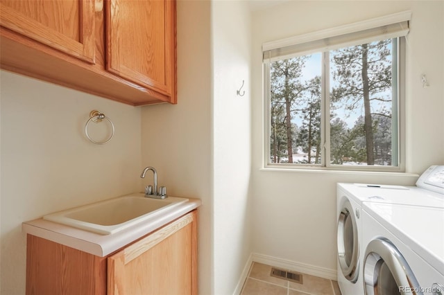 washroom featuring cabinet space, visible vents, a sink, washer and dryer, and tile patterned floors