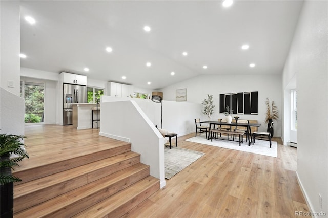 stairway featuring wood finished floors, baseboard heating, recessed lighting, and vaulted ceiling