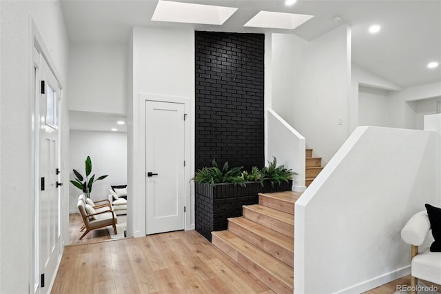 stairs featuring a skylight, wood finished floors, recessed lighting, and lofted ceiling
