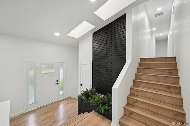 entryway featuring a skylight, light wood-type flooring, stairs, and recessed lighting