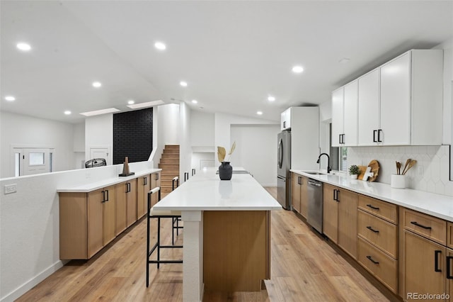 kitchen with appliances with stainless steel finishes, a sink, a kitchen island, a kitchen breakfast bar, and tasteful backsplash