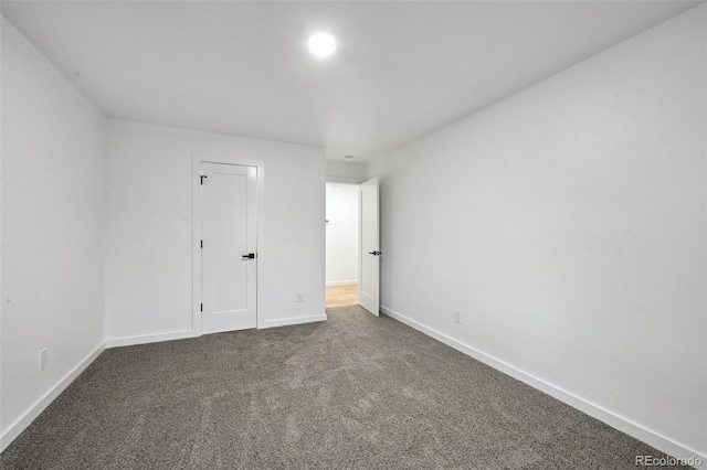 unfurnished bedroom featuring dark carpet and baseboards