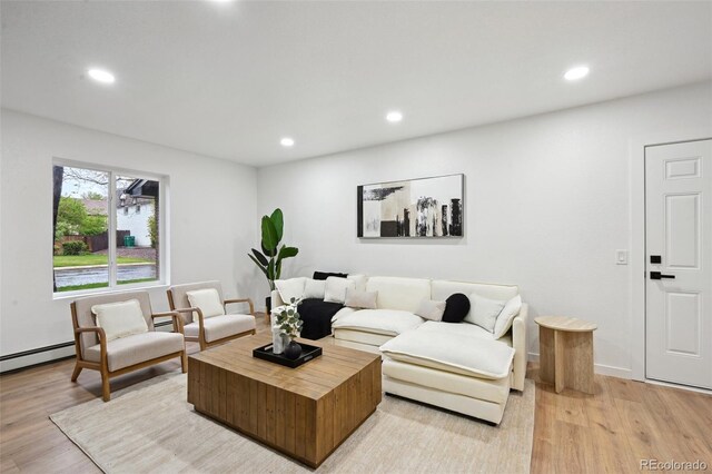 living area with recessed lighting, light wood-style flooring, and a baseboard heating unit