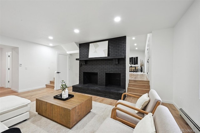 living area with a baseboard radiator, stairway, light wood finished floors, a fireplace, and recessed lighting